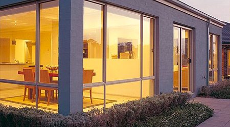 house with aluminium windows & sliding doors looking into dining room Outside view of a house with aluminium windows & sliding doors looking into dining area