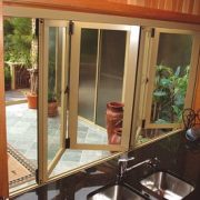Partially open bi-fold windows in a kitchen with black platform