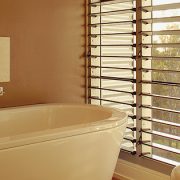 Open louvre windows in bathroom letting in the evening sun