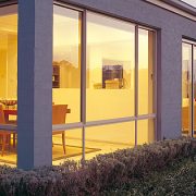 Outside view of a house with aluminium windows & sliding doors looking into dining area